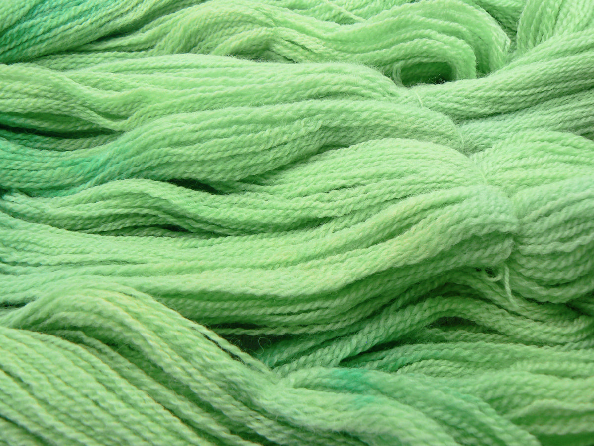 Close-up of light green yarn strands with soft, textured loops and a subtle gradient from pale mint to slightly deeper green.