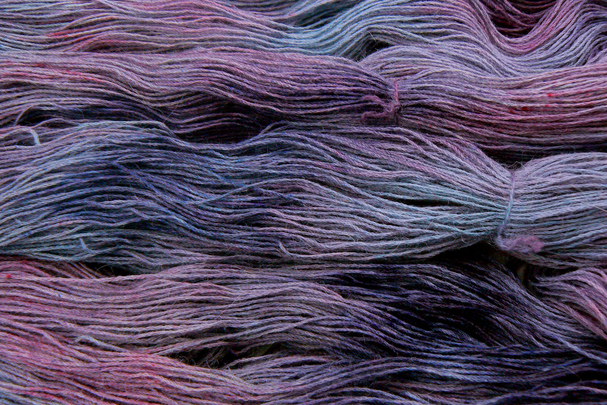 Strands of hand dyed yarn in shades of blue, purple and pink.