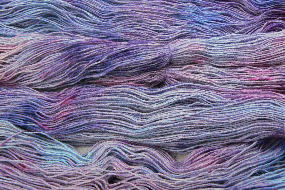 Close-up of variegated yarn strands in pastel shades of lavender, purple, pink, and light blue.