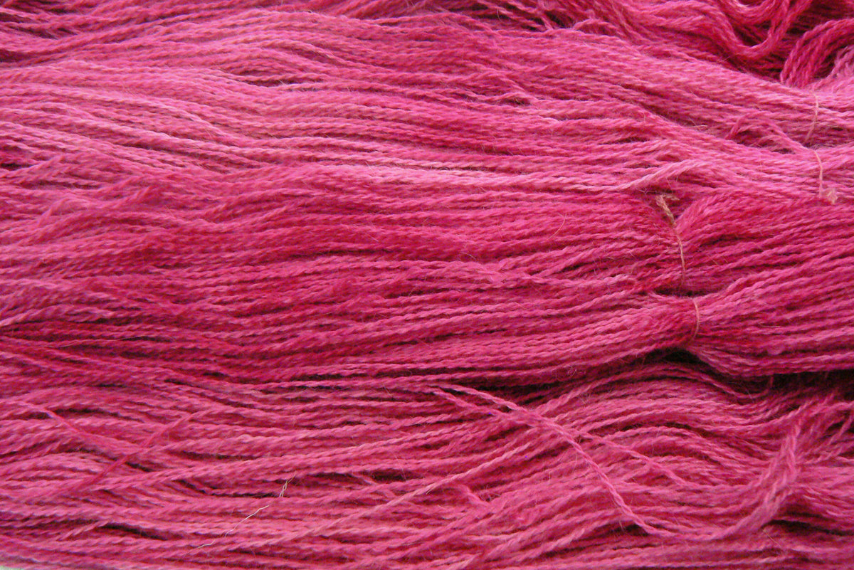 A close-up of bright pink yarn strands, showing the texture and colour of the fibre.